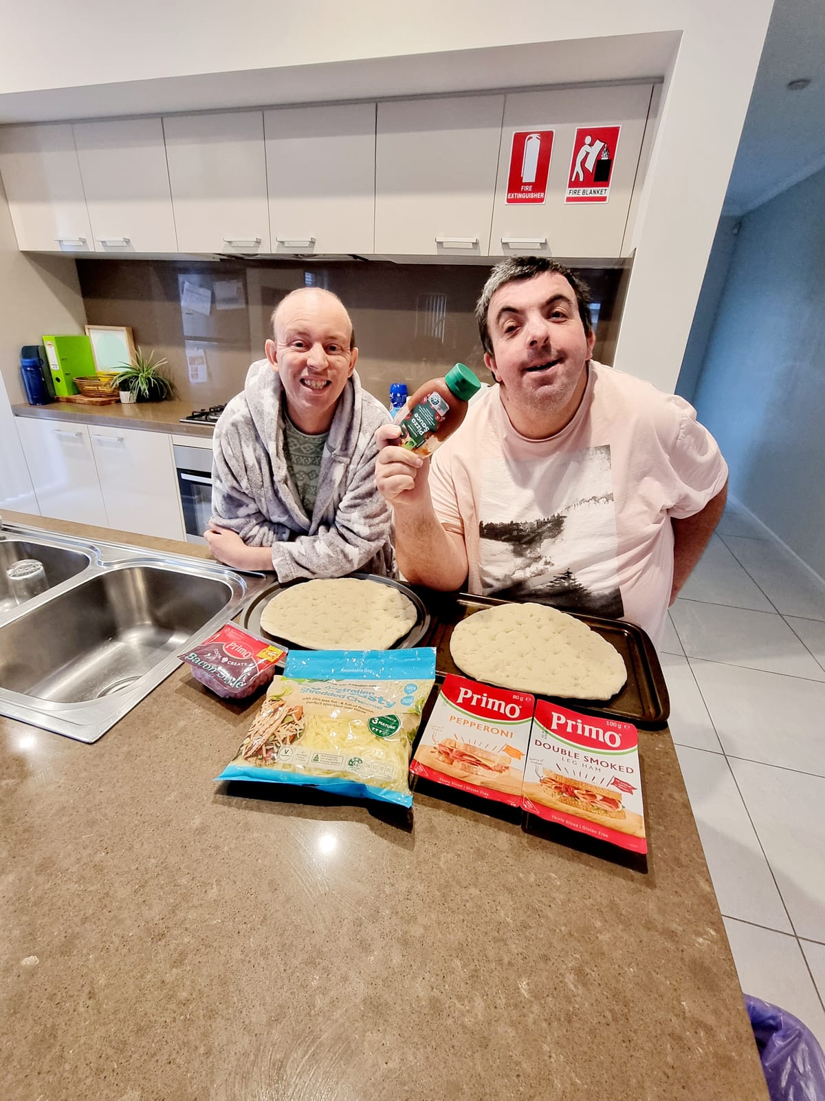 Two participants making pizza together in the kitchen of one of the homes.